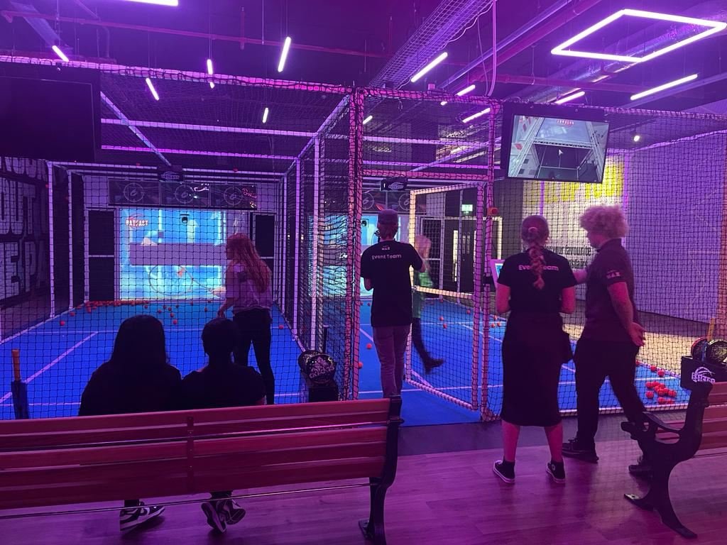 Players and staff inside the neon-lit batting cages at PowerPlay