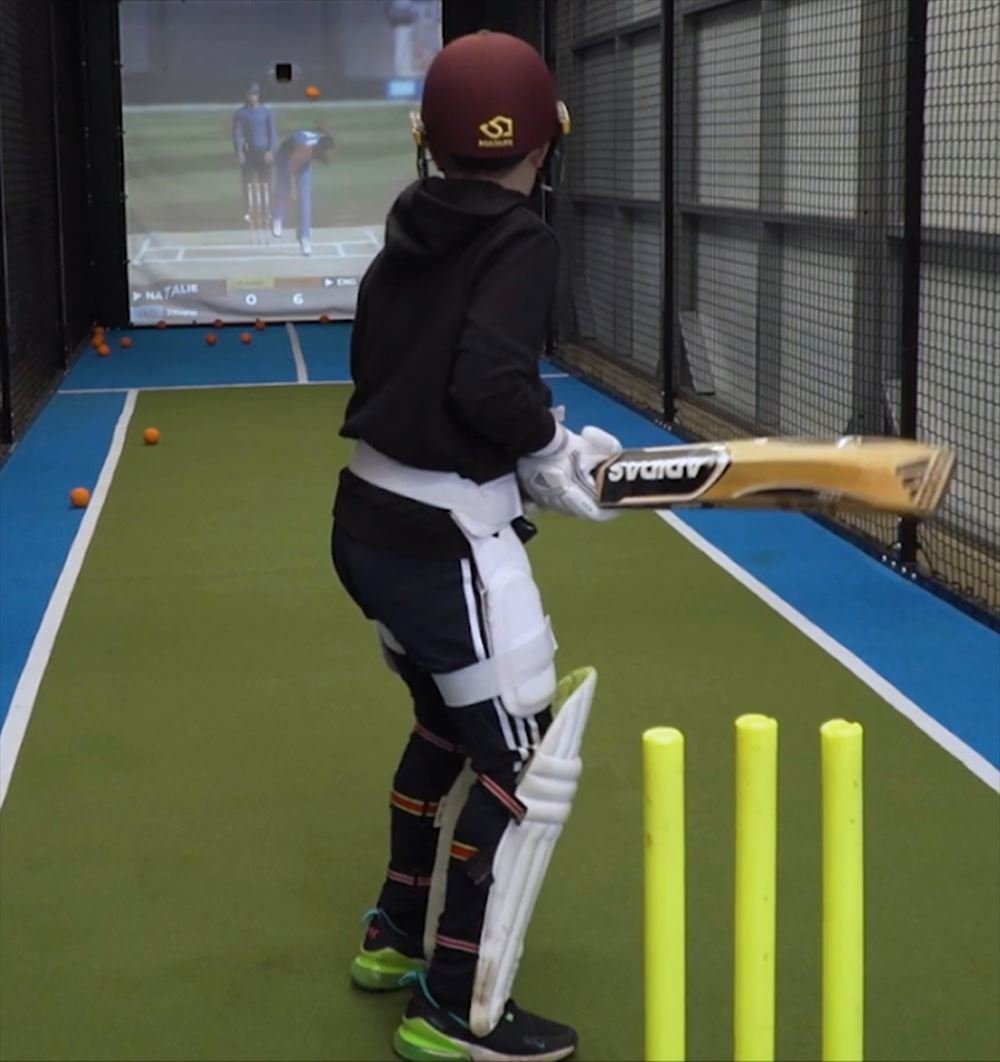 A young batter in pads and helmet in front of the stumps