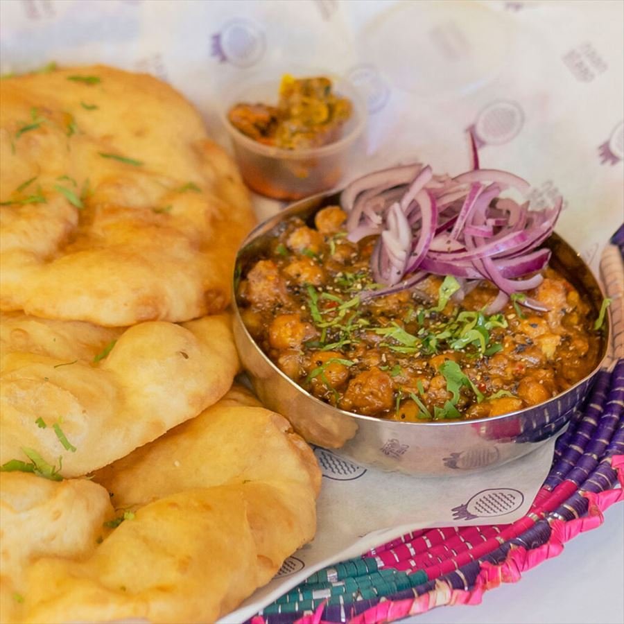 A bowl of chickpea curry served with fluffy fried bread