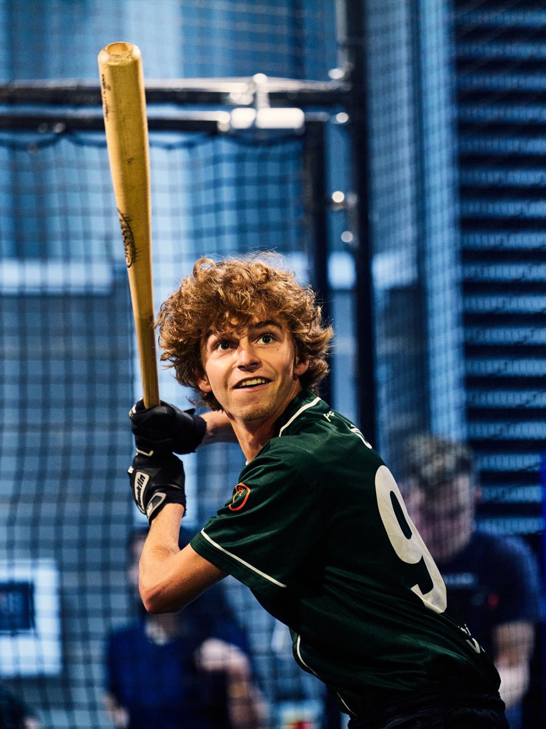 A young player in a green jersey lines up a swing in a PowerPlay batting cage