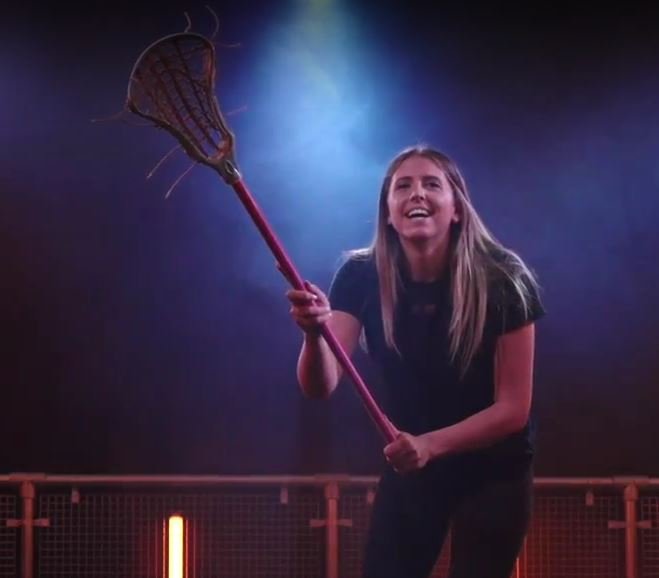 A lacrosse player lines up a shot under blue light
